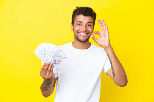 Jonge Braziliaanse Man Neemt Veel Geld Geïsoleerd Gele Achtergrond Toont — Stockfoto