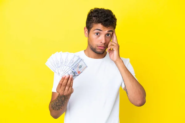 Jonge Braziliaanse Man Neemt Veel Geld Geïsoleerd Gele Achtergrond Denkend — Stockfoto