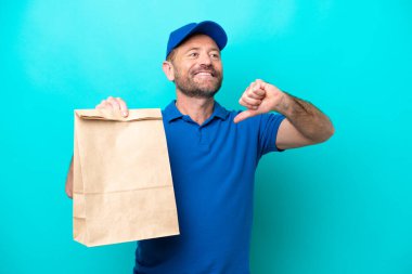 Orta yaşlı bir adam mavi arka planda izole edilmiş bir paket yiyecek alıyor gururlu ve kendinden memnun.