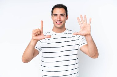 Beyaz arka planda izole edilmiş genç beyaz adam yediyi parmaklarıyla sayıyor