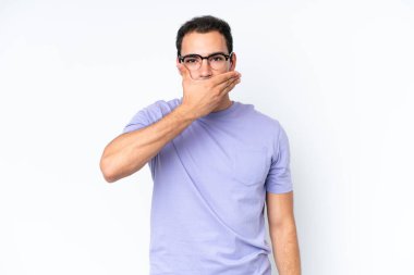 Beyaz arka planda izole edilmiş beyaz tenli genç bir adam ağızı eliyle kapatıyor.