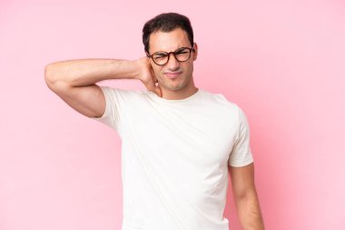 Pembe arka planda boynu ağrıyan genç beyaz bir adam.