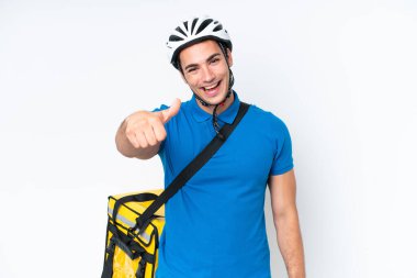 Beyaz arka planda izole edilmiş termal sırt çantalı beyaz tenli genç beyaz bir adam. Başparmakları havada çünkü iyi bir şey oldu.