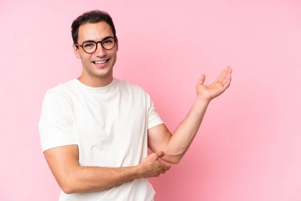 Jonge Blanke Man Geïsoleerd Roze Achtergrond Reikende Handen Aan Zijkant — Stockfoto
