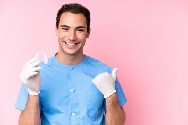 Dentista Caucasiano Segurando Aparelho Invisível Isolado Fundo Rosa Apontando Para — Fotografia de Stock