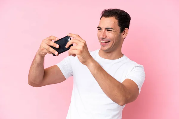 Νεαρός Καυκάσιος Άνδρας Απομονωμένος Ροζ Φόντο Παίζοντας Κινητό Τηλέφωνο — Φωτογραφία Αρχείου