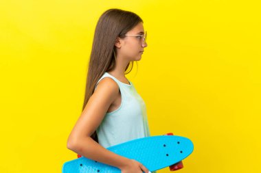 Küçük beyaz kaykaycı kız sarı arka planda izole edilmiş.