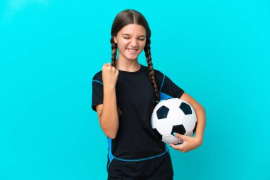 Mavi arka planda izole edilmiş beyaz bir kız futbol topuyla zaferi kutluyor.