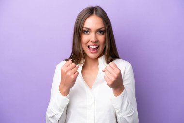 Mor arka planda izole edilmiş genç beyaz kadın galibiyeti kutluyor.