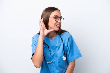 Young nurse caucasian woman isolated on white background listening to something by putting hand on the ear