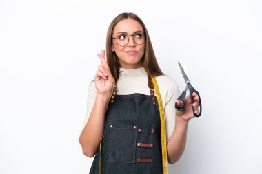 Young seamstress woman isolated on white background with fingers crossing and wishing the best