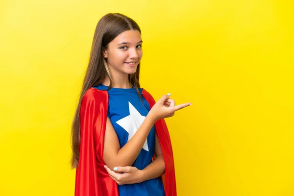 小さなCaucasianスーパーヒーロー女の子孤立しました上の黄色の背景指差し指へザサイド — ストック写真