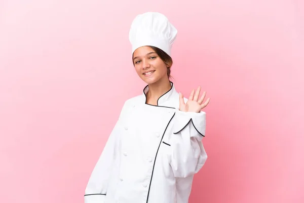Pequena Menina Chef Caucasiano Isolado Fundo Rosa Saudando Com Mão — Fotografia de Stock