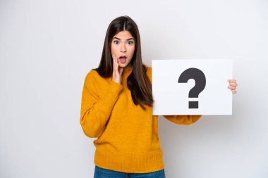 Beyaz arka planda izole edilmiş genç Brezilyalı bir kadın soru işareti sembollü bir levha tutuyor ve şaşırmış bir ifade var.