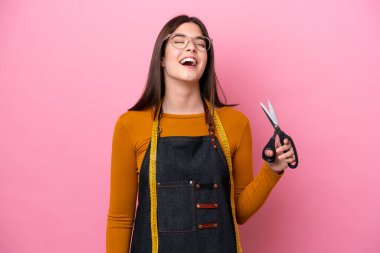 Genç Brezilyalı terzi kadın pembe arka planda yalnız gülüyor.