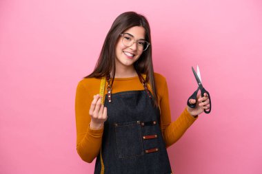 Pembe arka planda izole edilmiş genç Brezilyalı terzi kadın para hareketi yapıyor.