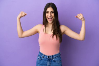 Mor arka planda izole genç beyaz kadın güçlü bir jest yapıyor.