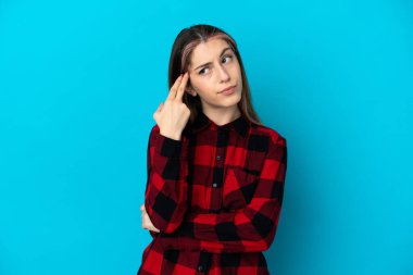 Genç beyaz kadın, mavi arka planda izole edilmiş ve intihar jesti yapmada sorun yaşıyor.