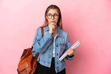 Pembe arka planda izole edilmiş beyaz bir kadın öğrencinin şüpheleri ve düşünceleri var.