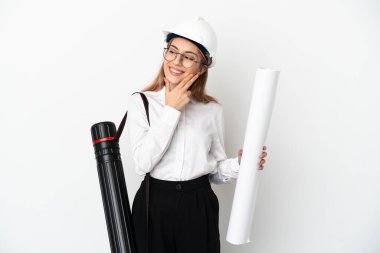 Miğferli ve elinde planları olan genç bir mimar beyaz arka planda izole edilmiş gülümserken yukarı bakıyor.