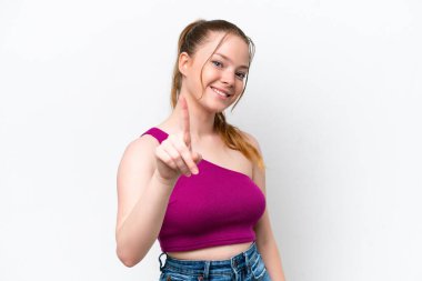 Beyaz arka planda izole edilmiş genç beyaz kız parmağını kaldırıyor ve gösteriyor.