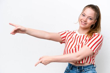 Beyaz arka planda izole edilmiş genç beyaz bir kız parmak göstererek bir ürün sunuyor.