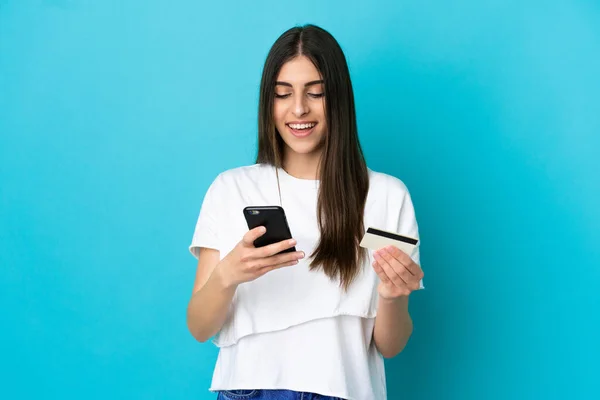 Jonge Blanke Vrouw Geïsoleerd Blauwe Achtergrond Kopen Met Mobiele Telefoon — Stockfoto