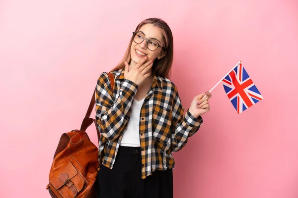 Молодая Латиноамериканка Держащая Флаг Великобритании Розовом Фоне Смотрит Вверх Улыбается — стоковое фото