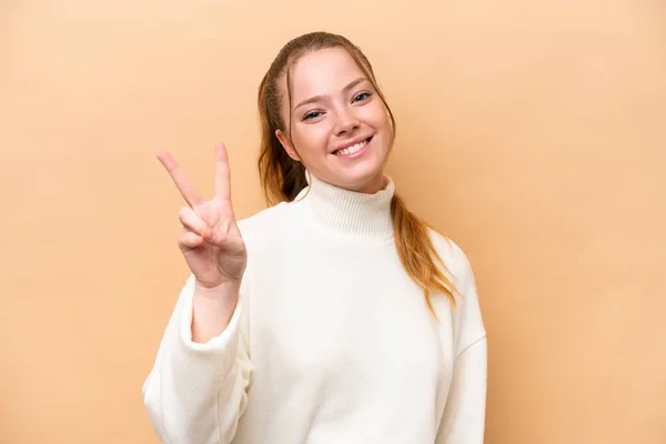 Jovem Caucasiana Isolada Fundo Bege Sorrindo Mostrando Sinal Vitória — Fotografia de Stock