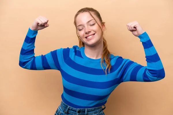 Joven Mujer Caucásica Aislada Sobre Fondo Beige Haciendo Gesto Fuerte —  Fotos de Stock