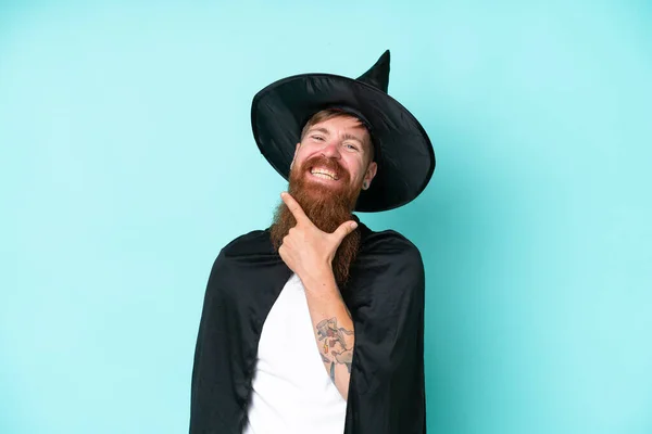 Young wizard in halloween isolated on blue background happy and smiling