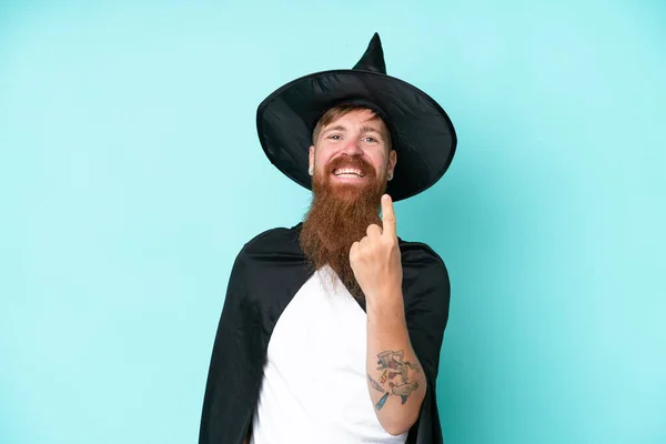 Young wizard in halloween isolated on blue background doing coming gesture