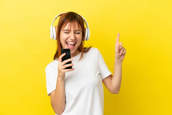 Redhead Κορίτσι Απομονώνονται Κίτρινο Φόντο Ακούγοντας Μουσική Ένα Κινητό Και — Φωτογραφία Αρχείου