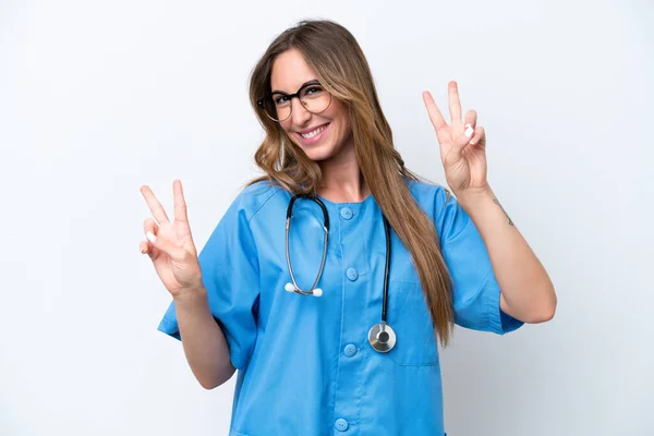 若い外科医の医師の女性は両方の手で勝利の兆候を示す青の背景に隔離 — ストック写真