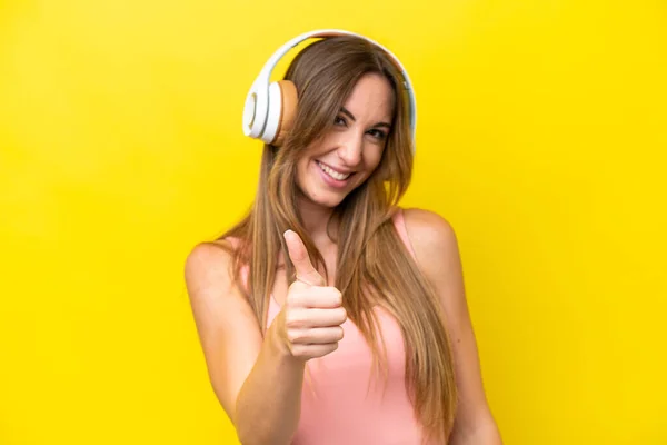Młoda Kaukaska Kobieta Odizolowana Żółtym Tle Słucha Muzyki Kciukiem Górze — Zdjęcie stockowe