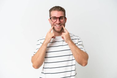 Beyaz arka planda izole edilmiş yakışıklı beyaz adam mutlu ve hoş bir ifadeyle gülümsüyor.