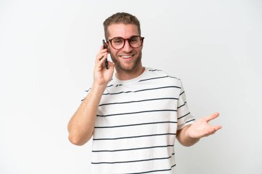 Beyaz arka planda izole edilmiş yakışıklı beyaz bir adam cep telefonuyla sohbet ediyor.