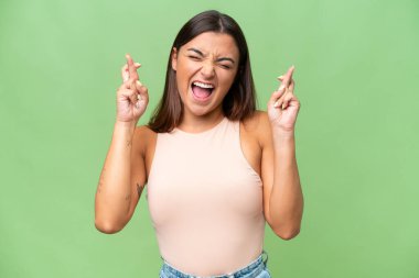 Genç beyaz kadın, yeşil krom arka planda izole edilmiş ve şans diliyor.