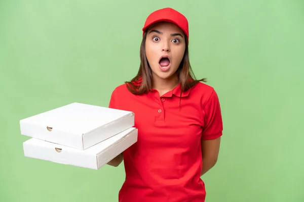 ピザ配達 Caucasian女性とともに仕事の制服ピザボックスを拾う隔離された緑色の背景に驚きの顔の表情 — ストック写真