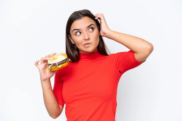 Młoda Kaukaska Kobieta Trzyma Hamburgera Odizolowany Białym Tle Mając Wątpliwości — Zdjęcie stockowe