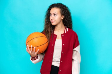 Arap basketbolcu kadın mavi arka planda izole edilmiş, yan tarafa bakıyor.