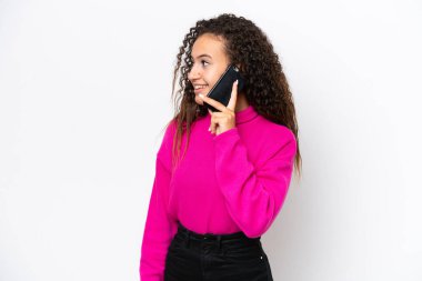 Beyaz arka planda izole edilmiş genç bir Arap kadın cep telefonuyla biriyle sohbet ediyor.