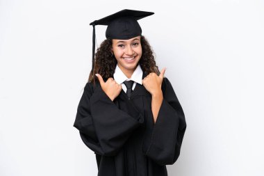 Genç üniversite mezunu Arap bir kadın beyaz arka planda izole edilmiş. Baş parmakları havada ve gülümsüyor.