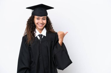 Üniversite mezunu genç bir Arap kadın beyaz arka planda izole edilmiş bir şekilde bir ürün sunmak için kenarı işaret ediyor.