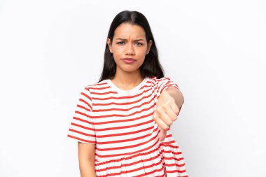 Beyaz arka planda izole edilmiş genç Kolombiyalı kadın olumsuz ifadeyle baş parmağını aşağı gösteriyor.