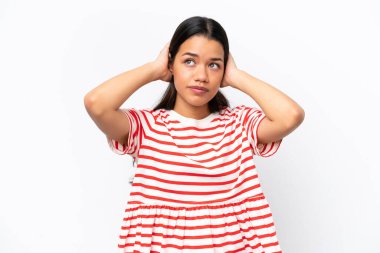 Beyaz arka planda izole edilmiş genç Kolombiyalı kadın hayal kırıklığına uğramış ve kulaklarını kapatmış.