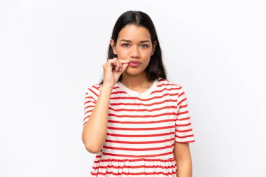 Beyaz arka planda izole edilmiş genç Kolombiyalı kadın sessizlik işareti gösteriyor.