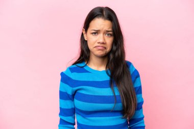 Genç Kolombiyalı kadın pembe arka planda üzgün bir ifadeyle izole edilmiş.