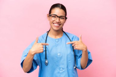 Genç Kolombiyalı hemşire, pembe arka planda soyutlanmış gururlu ve kendini beğenmiş.