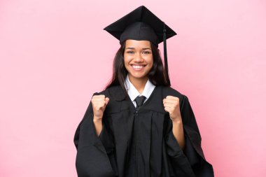 Üniversiteden mezun genç bir Kolombiyalı kadın pembe arka planda tek başına zaferi kutluyor.